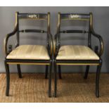A pair of Regency style parcel gilt and ebonised open armchairs, each painted with musical group,