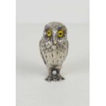 A silver novelty salt in the form of an owl, with yellow glass eyes, and its original spoon, by