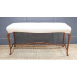 A mahogany framed window seat, with cream upholstered top, raised on delicately carved tapering legs