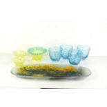 A group of glass ware to include three vaseline glass dishes and blue glasses. The large vaseline
