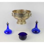 A silver plated ornate punch bowl with lion head loop handles together with two blue glass decanters