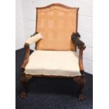 An 18th century and later walnut framed armchair, lacking upholstery, the wide carved arms adjoining
