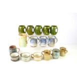 A collection of studio pottery mugs to include a set of five Holkham pottery green mugs.