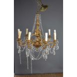 A gilt metal nine branch chandelier with scrolling arms and decorated with cherubs.