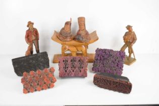 A group of vintage wooden printing blocks together with various wooden carvings of cowboys and