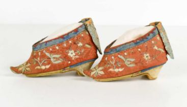 A pair of 19th century Chinese lotus shoes, embroidered with flowers, on a red ground with blue