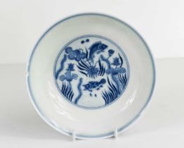 A Chinese blue and white dish, painted with fish against a wave ground, with waterlilies, in