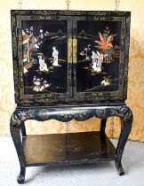 A Chinese black lacquered cabinet on stand, Chinoiserie decorated scenes to outer and inner door