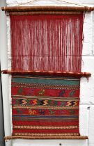 A woven woolen wall hanging, Native American, with geometric patterns and animals.