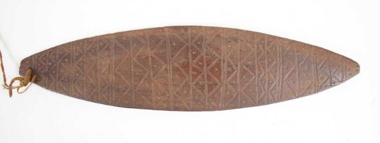 A tribal bullroarer, possibly Aboriginal, with geometric decoration, 28cm.