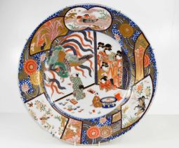 An Edo period Imari charger, the central circular panel with and artist painting a fire-bird, with