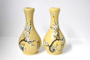 A pair of 20th century Chinese vases, each hand painted with white prunus blossom, and signed,