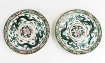 A pair of Chinese plates, depicting two dragons chasing flaming pearls, bordering a lotus flower,