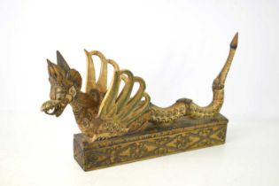 A Balinese carved wooden winged lion box, the top sliding off to reveal a compartment, with residual
