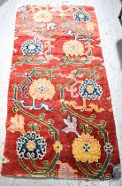 A 19th century Tibetan wool rug or wall hanging, natural dyes, the red ground decorated with