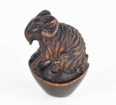 A Japanese carved wooden netsuke of a ram, with glass eyes and signed mother of pearl button to