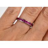A 14ct white gold and ruby half eternity ring, set with fifteen princess cut rubies, size N, 2.6g.
