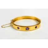 A Victorian 15ct gold and amethyst set bangle, the three amethysts in starburst setting, on plain