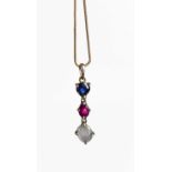 A silver set moonstone, ruby and sapphire pendant on fine twist silver chain, the trillion cut