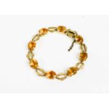 A 9ct gold bracelet set with eight oval cut citrines alternating with engraved double links, 18cm
