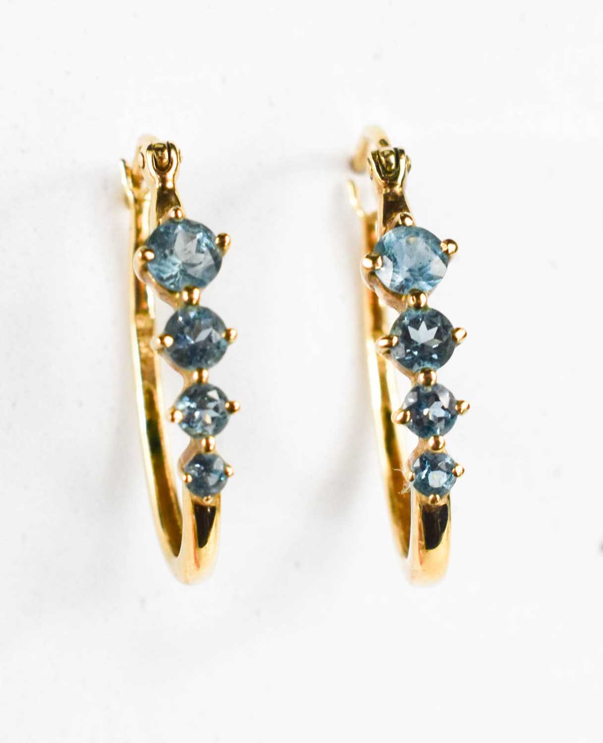 A pair of 9ct gold and aquamarine loop earrings, each set with four graduated stones, largest