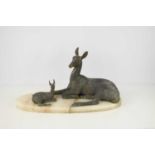 A 20th century spelter sculpture of a deer and fawn laying down, raised on an onyx base, 28cm high