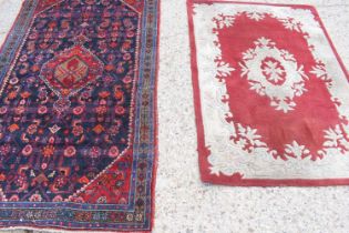 A Middle Eastern wool rug, red ground with stylised borders, 126cm by 217cm together with a red