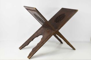 A late 19th century hardwood folding Quran stand, with pierced decorative ovals and fret-carved