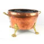 A large copper and brass coal bucket, twin handles and raised on four lion paw feet, 29cm high by