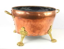 A large copper and brass coal bucket, twin handles and raised on four lion paw feet, 29cm high by