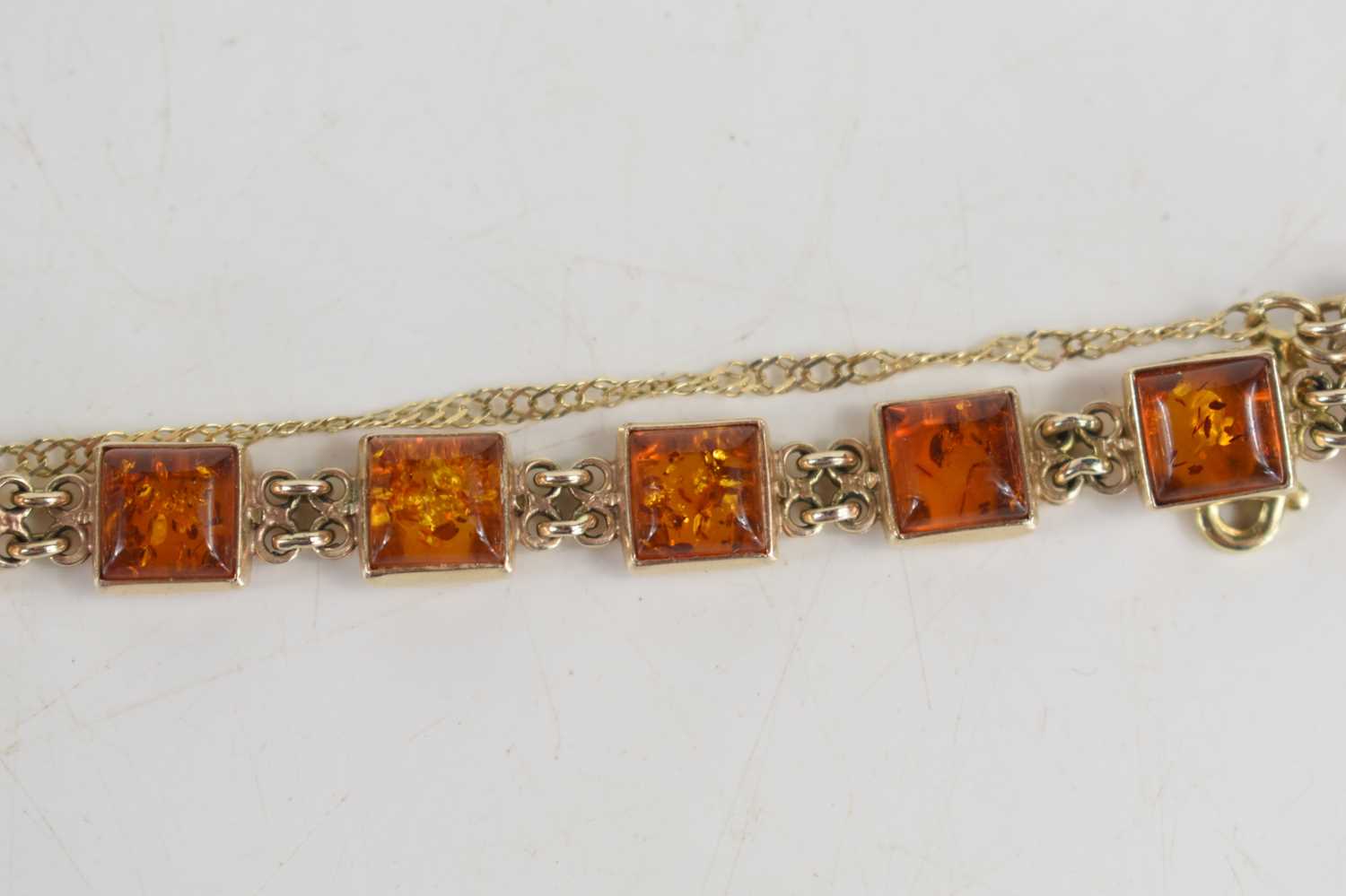A 9ct gold and amber bracelet, set with twelve small square panels of amber, 12.51g. [This lot has - Image 2 of 2