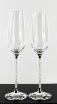 A pair of Swarovski crystal champagne flutes, the clear crystal fills the stems and the faceted