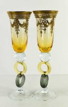 A pair of Bohemian style glass champagne flutes, with amber coloured bowl enhanced with gilded