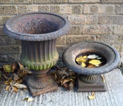 Two antique cast iron garden urn planters on circular footed base and square plinth, the larger