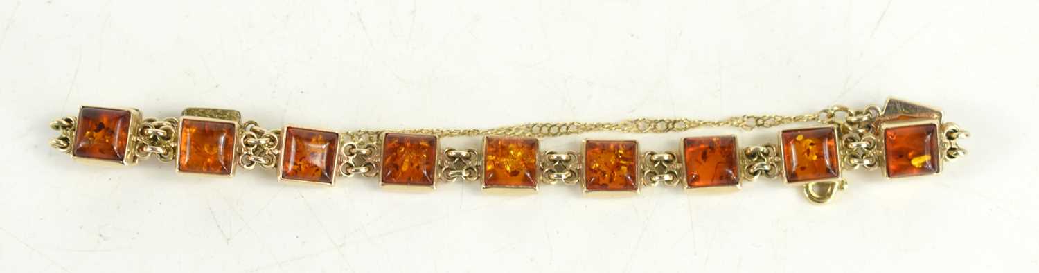 A 9ct gold and amber bracelet, set with twelve small square panels of amber, 12.51g. [This lot has
