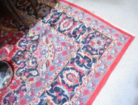 A large Middle Eastern red ground rug with stylised floral motifs to the centre and repeating