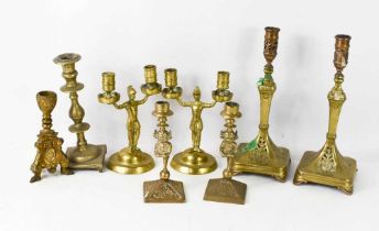 A group of brass candlesticks, a pair in the form of imps 18cm high, a pair of twin candlesticks,