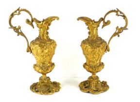 A pair of 19th century French ormolu bronze ewers, decorated with foliate scrolls and cherubs,
