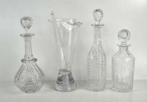 A group of three antique glass decanters together with a glass drinks mixing beaker, the base have a