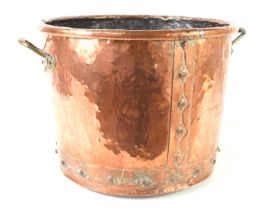 An antique copper cauldron with riveted seams and brass handles, 34cm high by 46cm diameter.