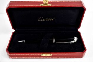 A Cartier ballpoint pen, black composite body and cap, palladium-finish details, blue resin