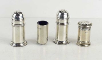 A group of three silver pepper shakers with glass liners together with another example missing lid.