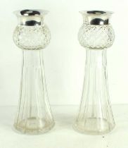 A pair of Edwardian cut glass vases with the silver rims above a tapering glass vase with star cut