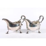 Pair of Georgian silver sauce boats with feathered edge and scroll handles raised on scallop shell