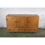 Ercol blonde tone model 429 type sideboard having three panel cupboard doors above two base drawers,