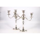 Pair of silver plated copper two branch, three light candelabra raises on stepped oval bases, 46cm