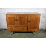 Ercol dark-tone model 467 sideboard with three panel cupboards doors above base drawer, 114cm long.