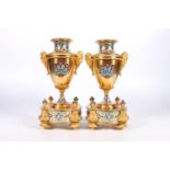 Pair of French gilt metal and enamel clock garniture supporting vases of urn shape with mask