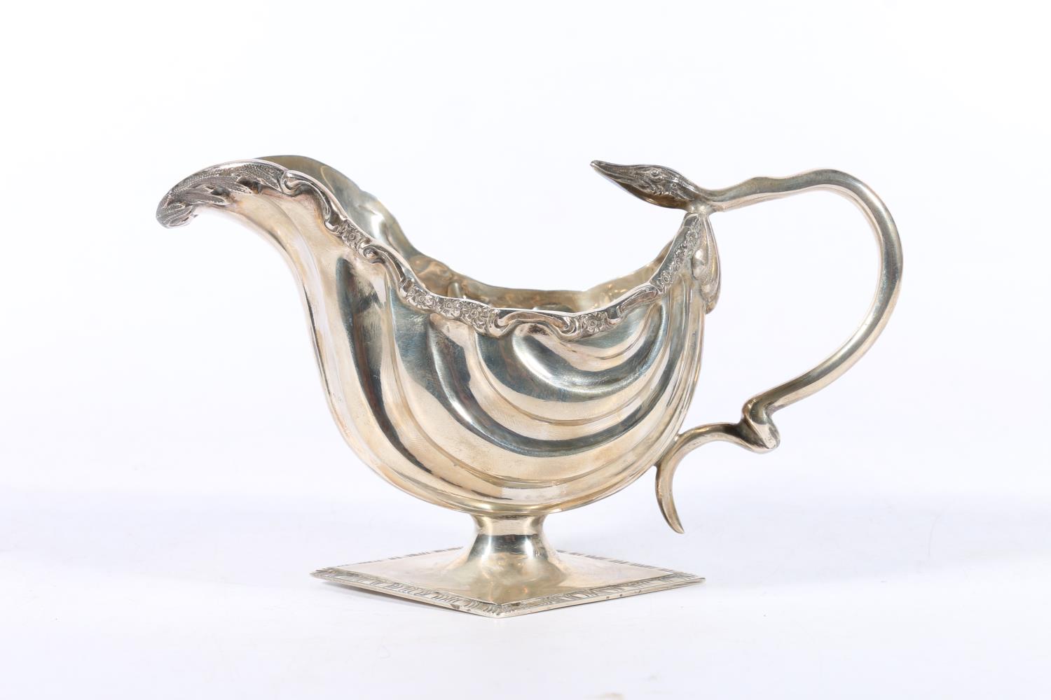 Edwardian silver cream jug with flower and scroll border and serpent handle raised on diamond shaped