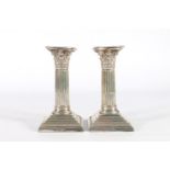 Pair of silver dwarf candlesticks of Corinthian column form raised on stepped bases by William